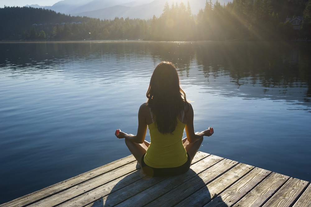 girl doing yoga by the lake