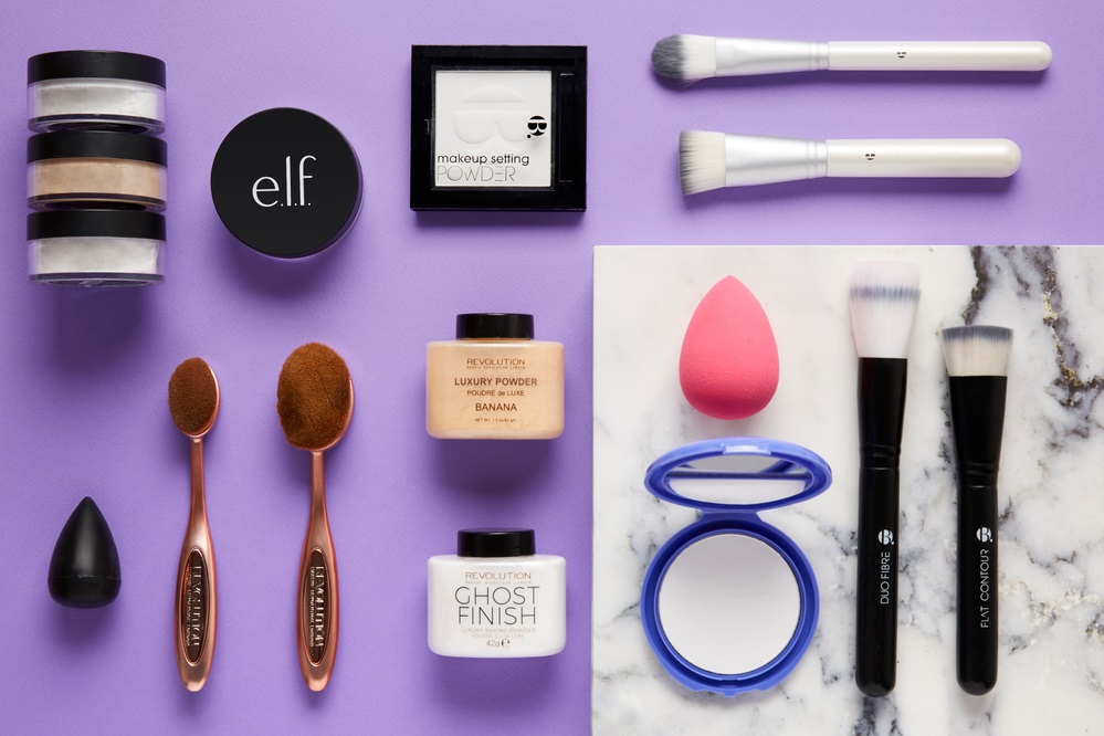Flat lay of face powders, makeup brushes and blending sponges