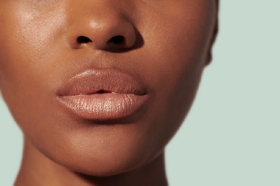 Zoomed in plump lips with brown lip gloss. 