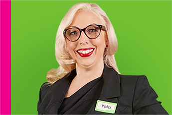 Image of a smiling lady with long blonde hair, wearing a black suit, glasses and a name tag with 'Yola' written on it.